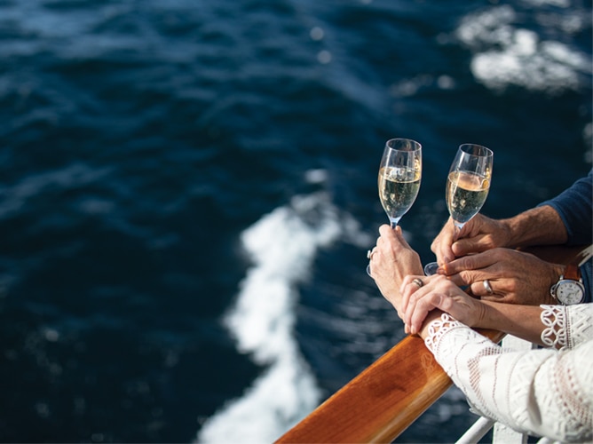 una pareja disfrutando de una copa de champán desde el balcón con vista al mar