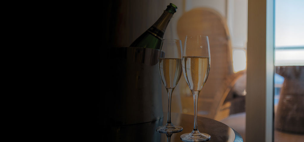 two flutes filled with champagne with bottle in ice bucket