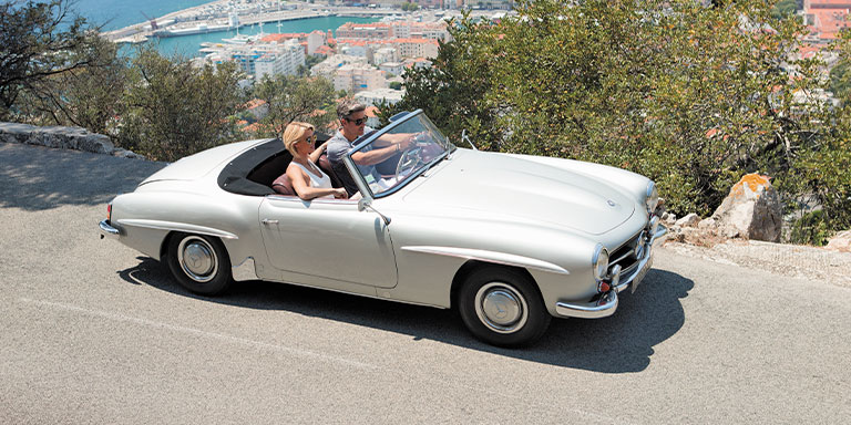 a couple driving in a convertable through scenic streets